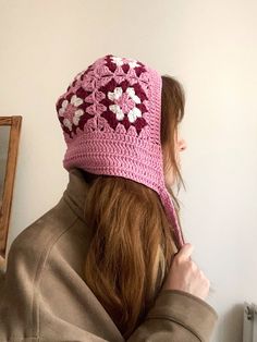 a woman wearing a pink crocheted hat with flowers