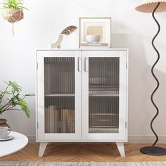 a white cabinet sitting next to a potted plant on top of a hard wood floor