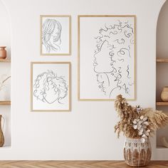 three framed drawings hang on the wall next to a vase with dried flowers in it