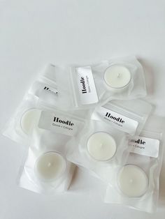 four tea lights in plastic bags on a white surface with the packaging labelled'hoddie '