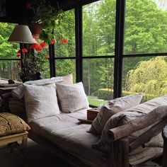 a living room filled with furniture and lots of windows next to trees in the background