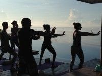 silhouettes of people doing yoga in front of the ocean