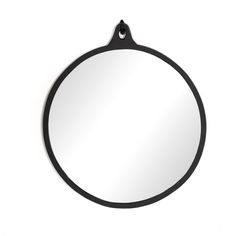 a round mirror hanging from the side of a white wall with a black hook on it