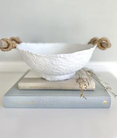 a white bowl sitting on top of a stack of books next to a blue book