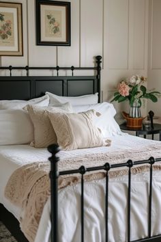 a black iron bed with white sheets and pillows