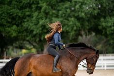 a woman riding on the back of a brown horse