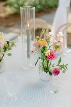 Sunset light touching lit candle and delicate table top flowers. Spring wedding flowers.