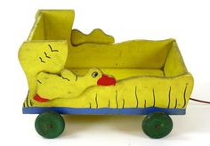 a yellow wooden toy with a dog in it's bed and wheels on the ground