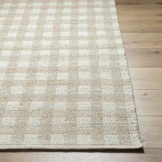 a beige and white checkered rug on the floor with wood floors in the background