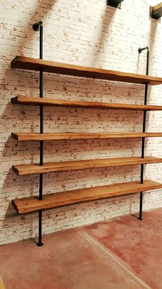 an empty room with some shelves on the wall and lights hanging from the brick wall