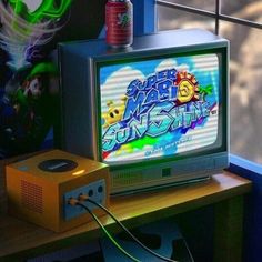 an old tv sitting on top of a wooden table next to a window with the words super mario sunshine written on it