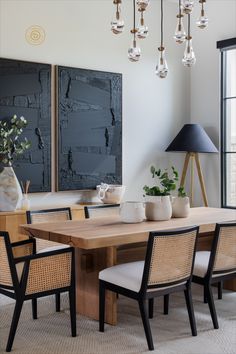 a dining room table with four chairs and two vases on the table next to it