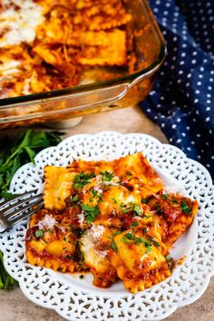 a white plate topped with lasagna next to a casserole dish