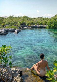 a woman sitting on the edge of a body of water