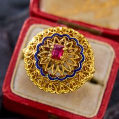 This highly detailed ring from Italy has ornate pierced goldwork accented by an undulating blue enamel border, and centered with a rectangular step cut ruby. The rich color of the gold has a very luxurious feeling. The ring is crafted in 14k yellow gold and is currently a size 6. Please note that the ruby has natural surface-reaching inclusions and that there is a slight nick in the blue enamel, neither of which affects wearability. Antique Yellow Gold Jewelry With Meenakari, Gold Luxury Ceremonial Enamel Ring, Luxury Gold Enamel Ring For Ceremonial Occasions, Luxury Gold Ceremonial Enamel Ring, Ornate Yellow Gold Filigree Ring With Gemstone, Ornate Gold Ruby Ring, Ceremonial Yellow Gold Ruby Ring With Intricate Design, Ceremonial Gold Ruby Ring With Intricate Design, Luxury Gold Ruby Ring With Intricate Design