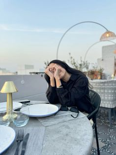 a woman sitting at a table with her head in her hands