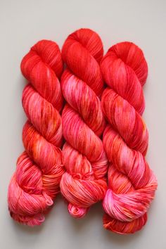 several skeins of red and pink yarn on a white surface with space for text