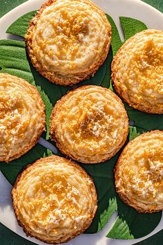 four small pies on a plate with green leaves