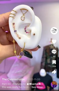 a person holding up a fake ear with jewelry on it