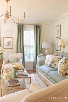 a living room filled with furniture and a chandelier hanging from the ceiling in front of a window