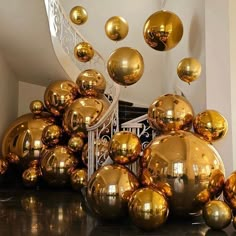 many shiny gold balls are on the floor next to a spiral stair case and railing