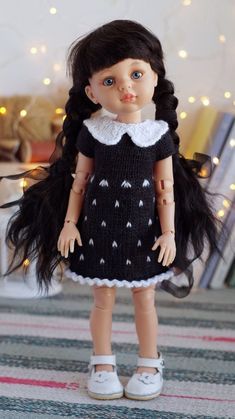 the doll is wearing a black dress with white trims and has long dark hair