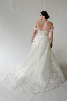 a woman in a white wedding dress is looking off to the side with her back turned