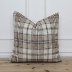 a brown and white plaid pillow sitting on top of a wooden floor