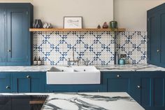 a kitchen with blue cabinets and marble counter tops, including a white sink in the center