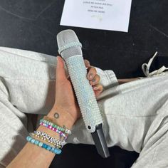 a person holding a microphone in their hand with bracelets on it's wrist