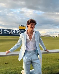 a man in a blue suit and white shirt posing for the camera with his arms outstretched