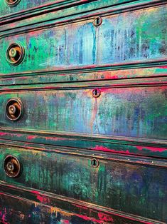 an old green and blue dresser with metal knobs