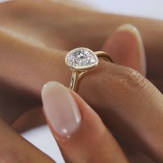 a close up of a person's hand holding a ring with a diamond on it