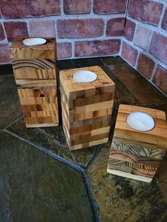 three wooden boxes sitting next to each other on a floor in front of a brick wall