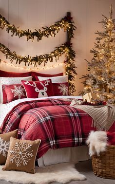 a bedroom decorated for christmas with red and white bedding, plaid comforter, pillows, trees and lights