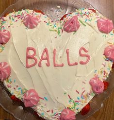 a heart shaped cake with the word balls written in frosting and sprinkles