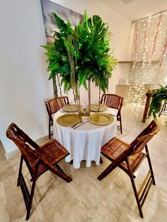 there is a table set for two with chairs and a potted plant in the center