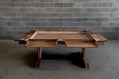 a wooden table with two drawers on it in front of a brick wall and floor