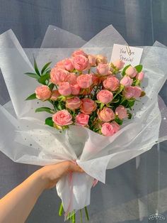 a person holding a bouquet of pink roses