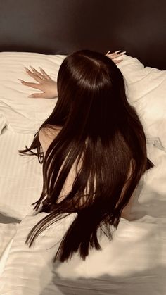 a woman laying on top of a bed covered in white sheets