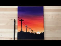 the painting is being displayed next to a pen and paper with an image of power lines on it