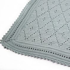 a crocheted blanket is laying on top of a white surface with black dots