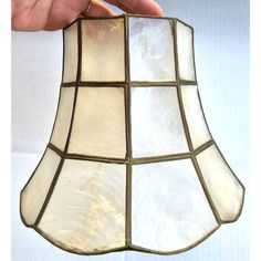 a hand holding a stained glass lamp shade