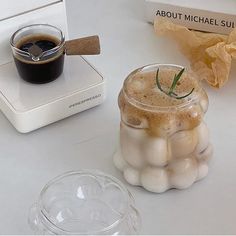 a cup of coffee sitting on top of a counter next to a container with marshmallows in it