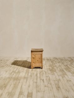 a small wooden box sitting on top of a hard wood floor next to a wall