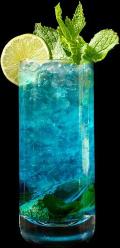 a tall glass filled with blue liquid and lime