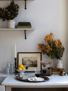 a kitchen counter topped with plates and bowls filled with food next to a wall mounted shelf