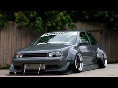 a gray car parked in front of a wooden fence