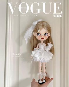 a hand holding a doll on the cover of a magazine