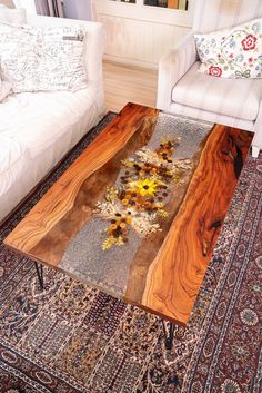 a coffee table with flowers on it sitting in front of a white couch and chair